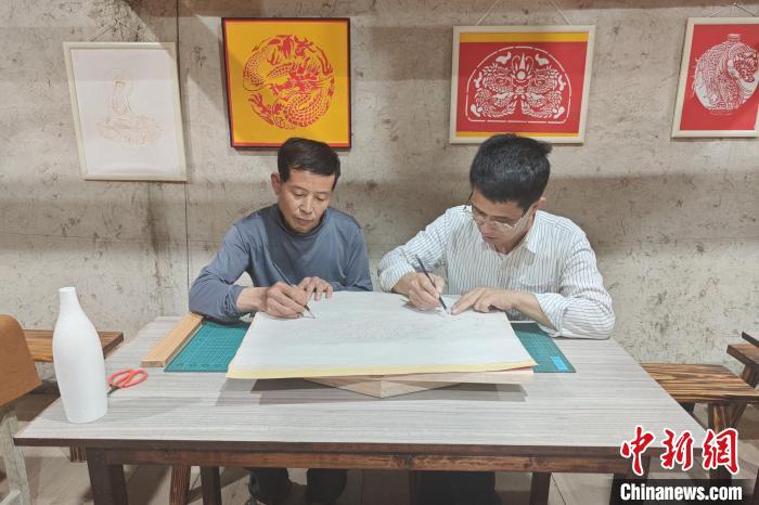 15日，林长聪(右)和伙伴一起创作刻纸作品《猛虎下山》。吴冠标 摄