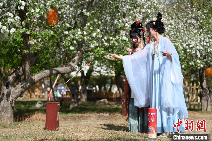 洛铉(右)与云柒在杏花树下玩投壶游戏。　中新网记者 刘文华 摄