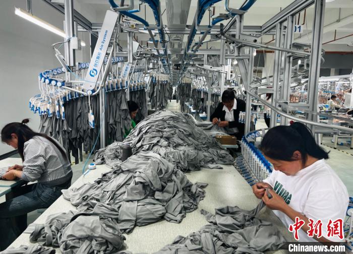 图为云南艺心服饰有限公司工人在缝织车间缝织衣服。时文枝 摄