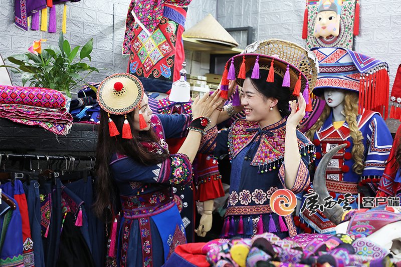 2024年4月2日，“三月三”将至，环江毛南族自治县不少民族服饰店迎来了销售热潮。图为群众在店内试穿民族服饰。阳新英 摄