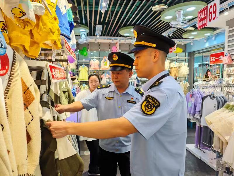 图为4月17日，该局崇义街道市场监管所执法人员在一家专卖店检查服装质量。（戴庆盈 文光辉）