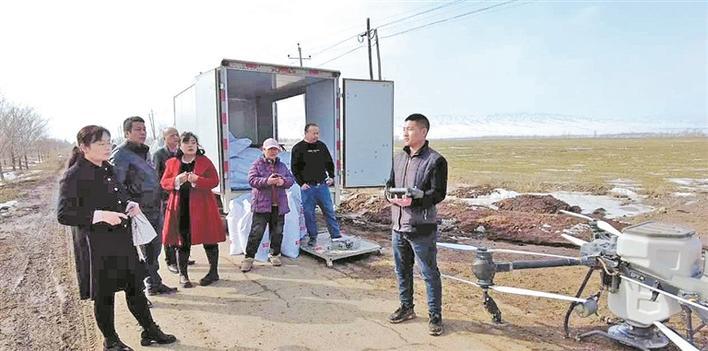 在六师军户农场，中华财险新疆分公司为职工群众聘请的技术顾问（右一）正用无人机为冬小麦施肥（资料图片）。