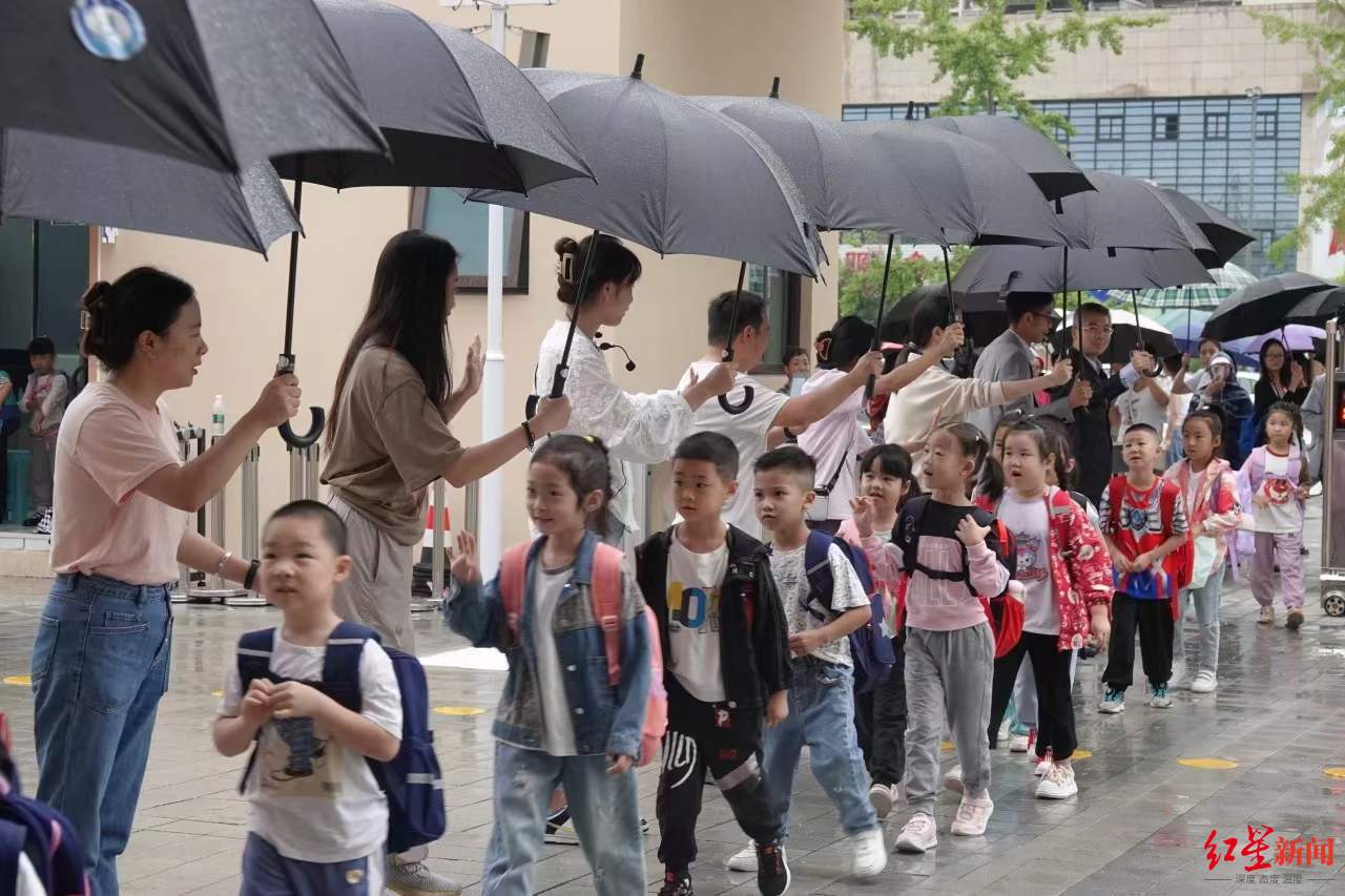 ▲成都市双流区九江新城小学的老师们为孩子们撑伞