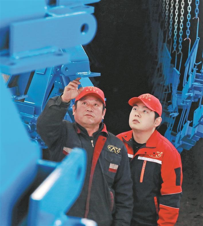4月1日，张和平（左）给儿子张桐宇浩介绍农机具新型喷涂工艺的优势。张西安 摄