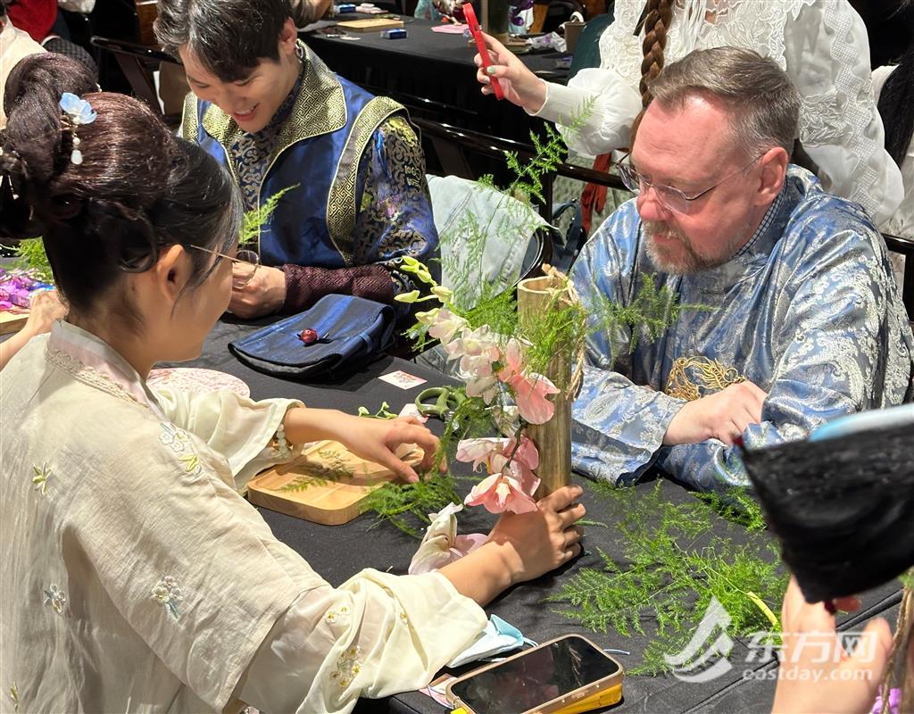 裴文德（右一）身穿淡蓝色华服正在学习如何制作中式插花。