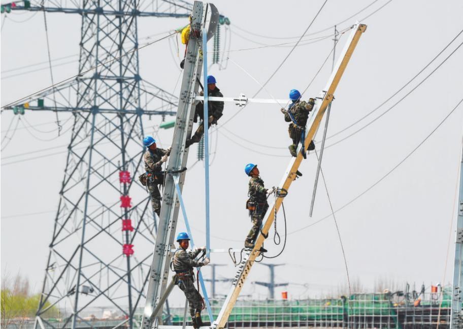 电力工人正在开展新输电杆塔的组建、安装工作。
