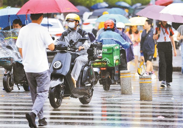 4月22日中午，福田区莲花西路，市民冒雨出行。 深圳晚报记者 陈玉 摄