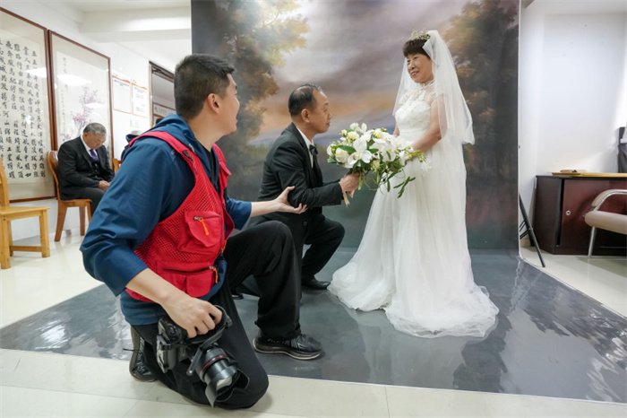 2024年4月24日，福州鼓楼区安泰街道乌山社区的工会驿站里，摄影志愿者正在给老人设计拍照造型。图片来源：视觉中国