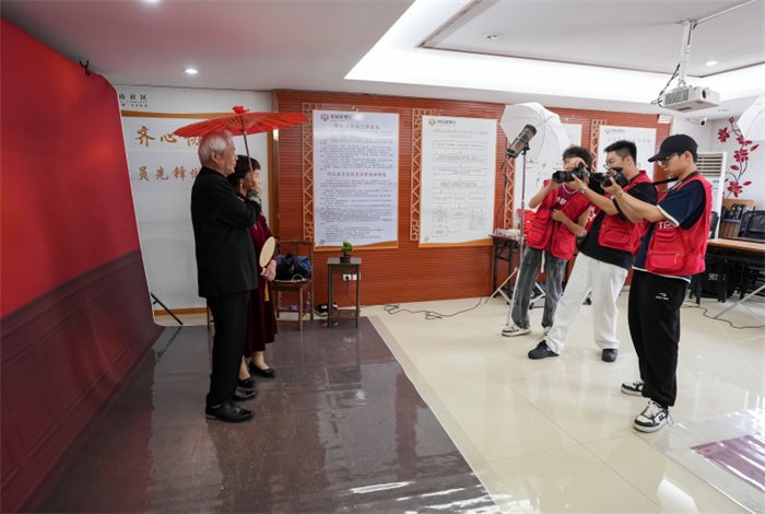 2024年4月24日，福州鼓楼区安泰街道乌山社区的工会驿站里，志愿者给老人拍摄婚纱照。图片来源：视觉中国