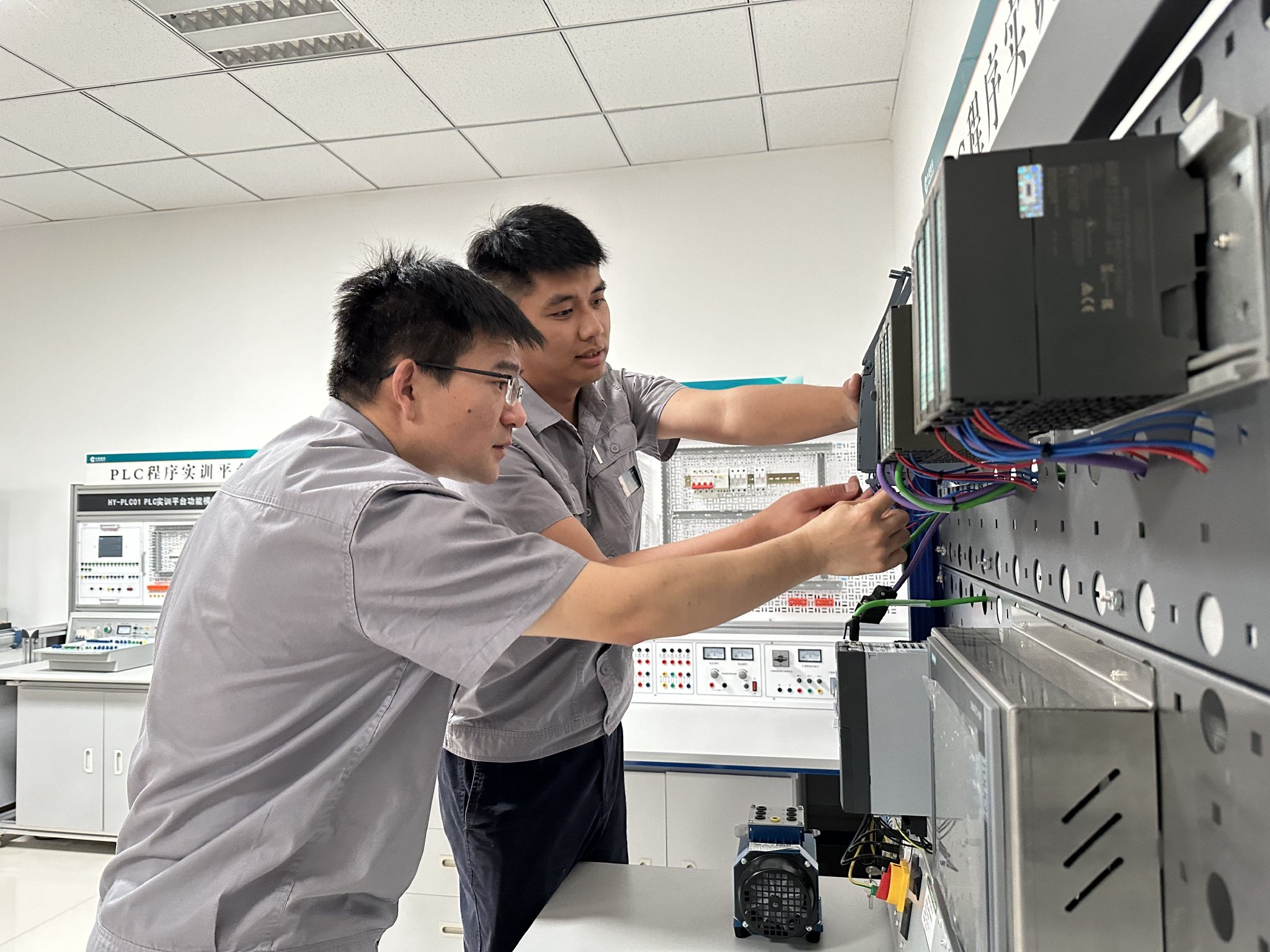 王楠楠（左）带“徒弟”李超学习使用PLC实训平台