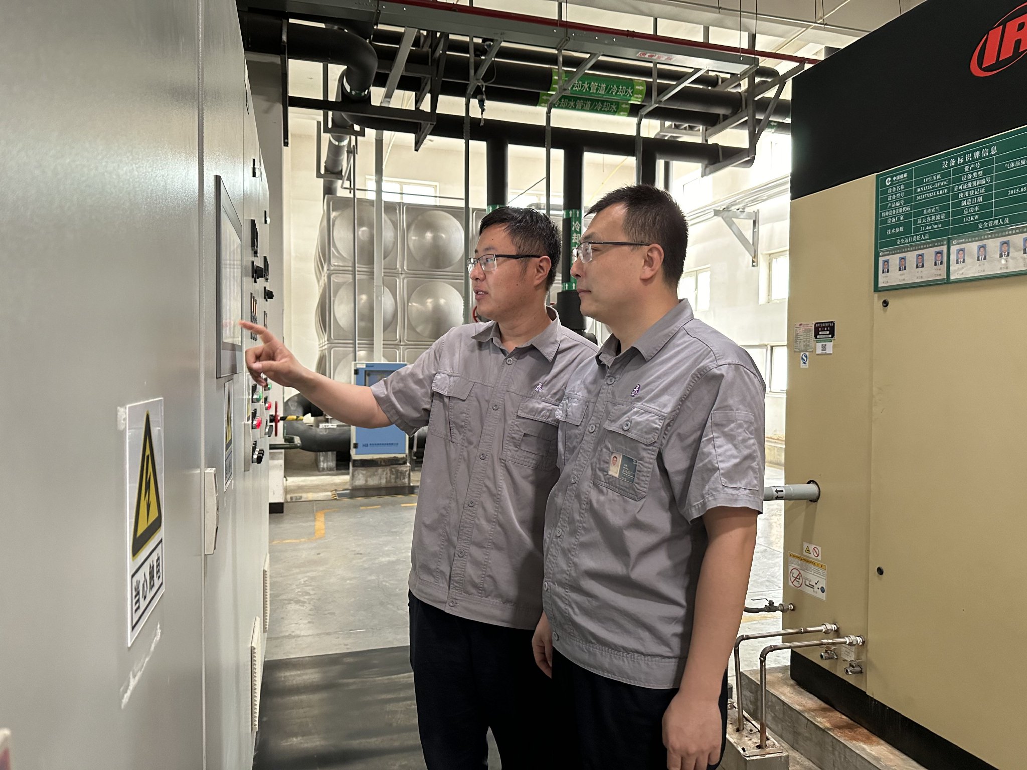 车间员工赵宗峰（左）、步刚查看能源设备运行参数，查找创新节能方向