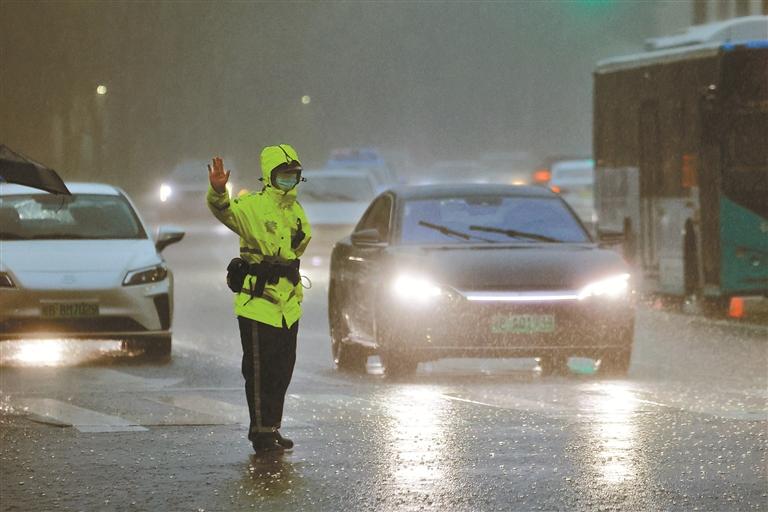 交警在莲花路和新洲路交会处冒雨疏导交通。 深圳晚报记者 陈玉 摄