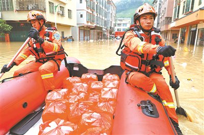 4月22日，广东江门消防救援支队队员划冲锋舟给英德市连江口镇居民送饭
