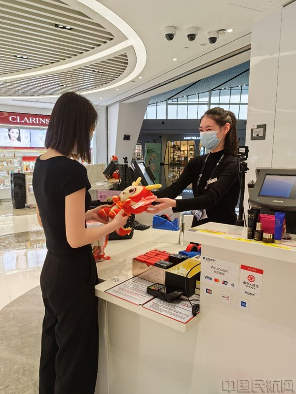 机场工作人员向旅客赠送吉祥物（赵淼/摄）