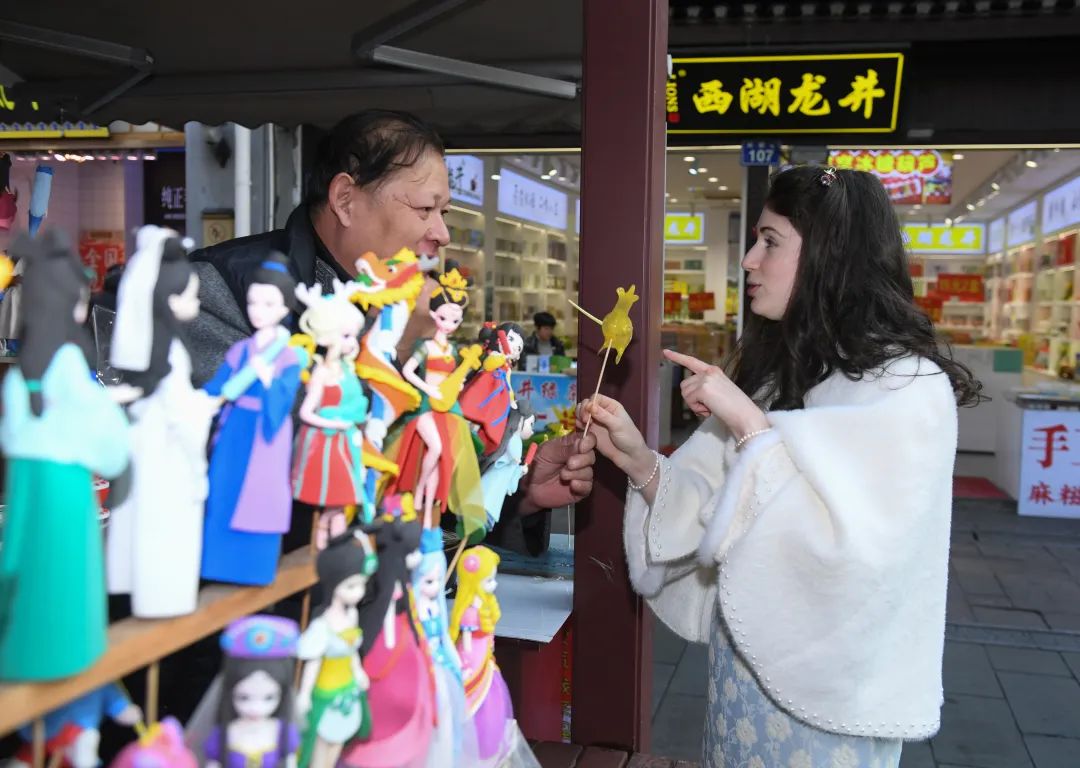 游客在杭州清河坊和糖塑艺人交流。翁忻旸摄（新华社）
