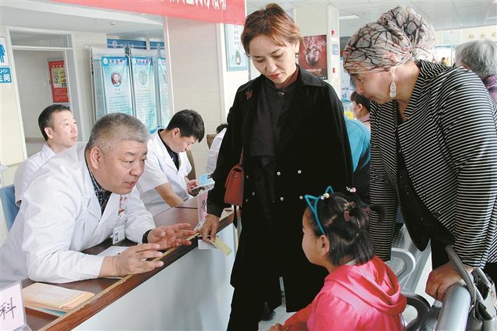 在十师北屯市总医院开展的一次义诊活动中，聂信胜（左）在询问患者的病情（资料图片）。 冯韬 摄