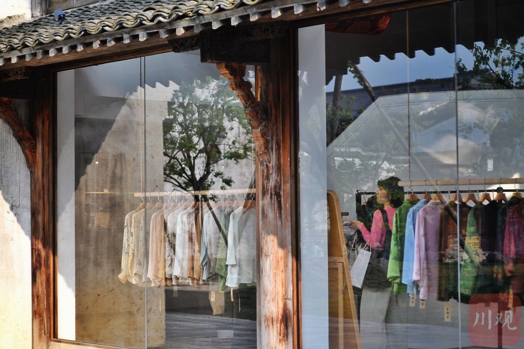 4月26日，游客在古镇里的时尚服饰店里选购新款服饰。