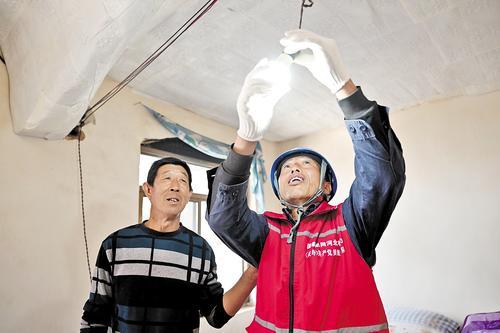 4月16日，邢海明（右）为村民更换电灯泡。