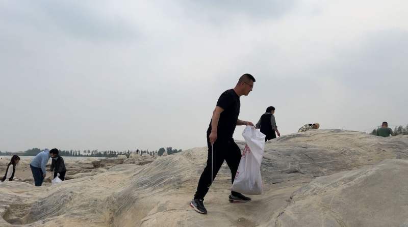 志愿者到巨石滩景观处捡垃圾。新京报记者 陈璐 摄
