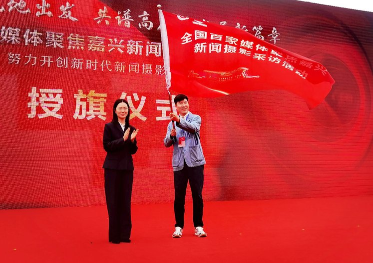 图为：嘉兴市委宣传部副部长、网信办主任俞奕凌为媒体代表授旗。
