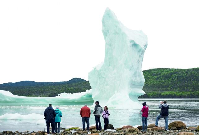 图片说明： 人们在纽芬兰岛海岸看冰山。
