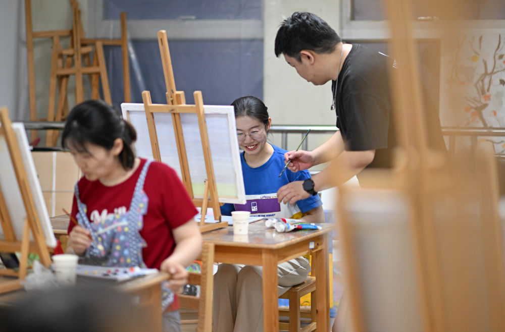 ↑4月26日，在天津青年宫，青年夜校教师陆圣指导学员吕昕蕾学习油画