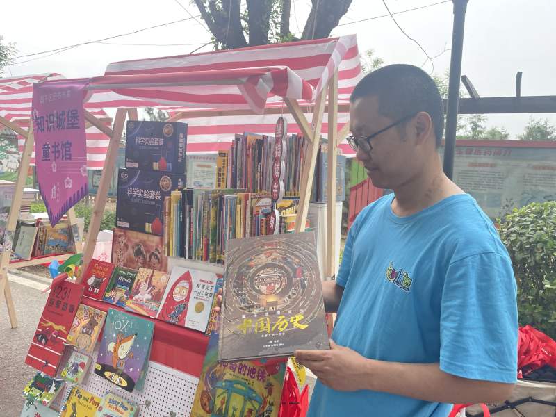 摊位前，王先生向记者介绍自己带来的儿童书籍。新京报记者 田杰雄 摄