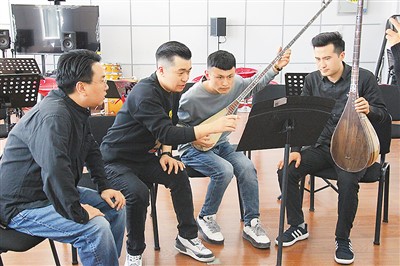 新疆艺术学院师生为中国交响乐团作曲家杨帆（左一）展示弹拨尔乐器。