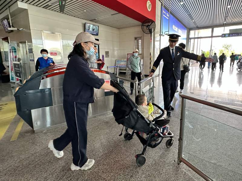 工作人员协助一位推婴儿车的乘客走无障碍通道。新京报记者 王贵彬 摄