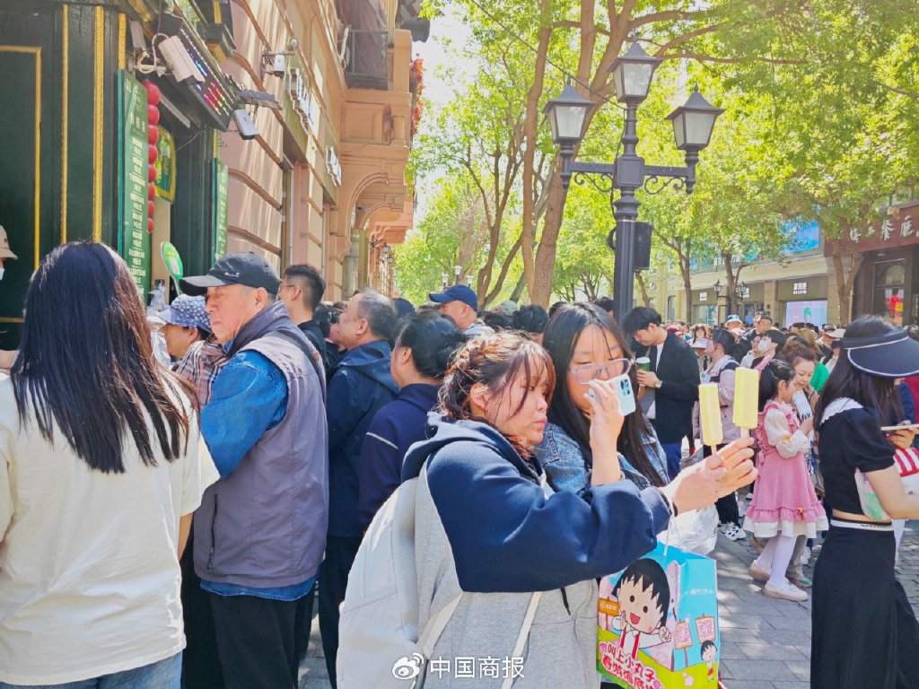 游客举起马迭尔冰棍拍照打卡。