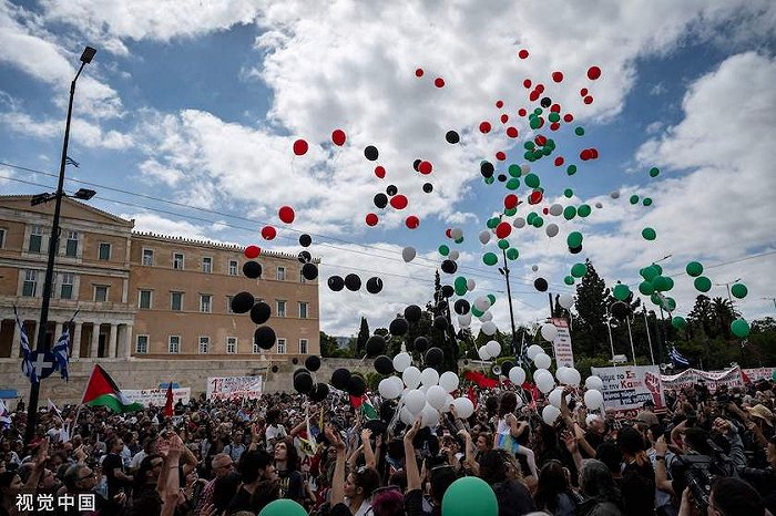 2024年5月1日，希腊雅典，国际劳动节集会上，抗议者在希腊议会前放飞带有巴勒斯坦国旗颜色的气球。图源：视觉中国