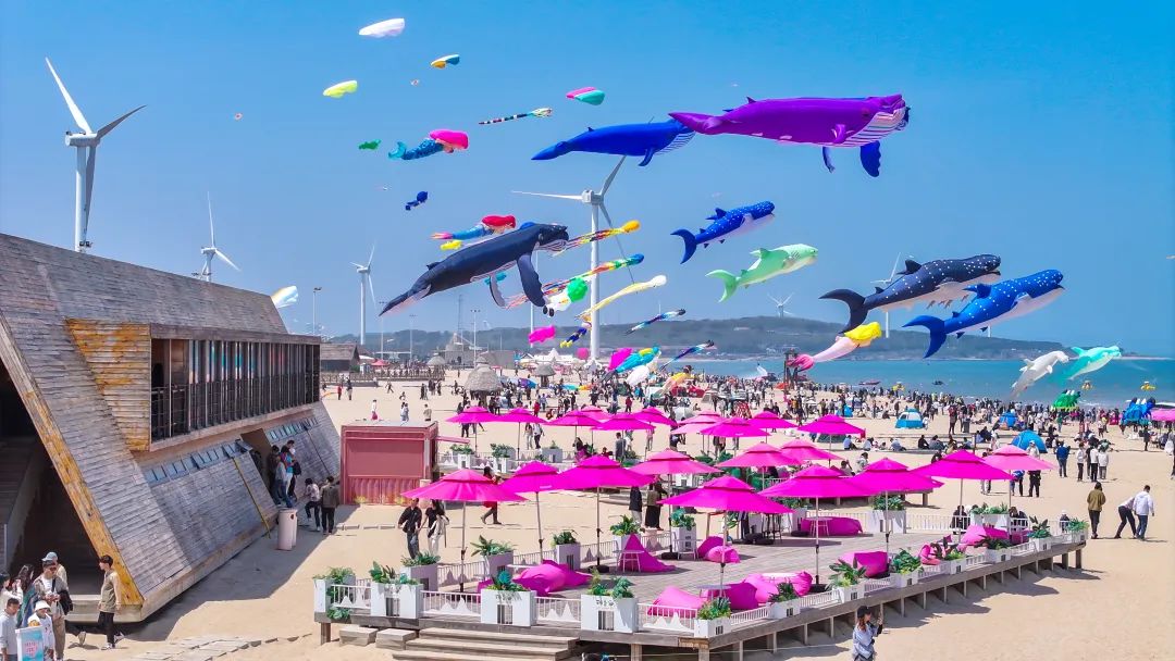 1日，在山东省荣成市那香海景区一处沙滩，游客们在观看风筝秀表演。李信君摄（中经视觉）