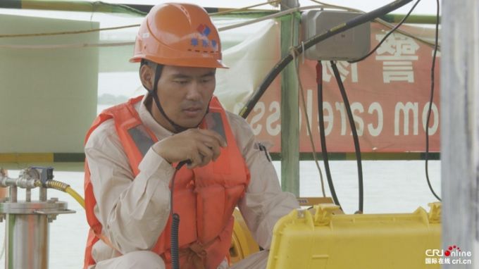 ▲刘庆在监看潜水员在水下工作实时视频并与其沟通
