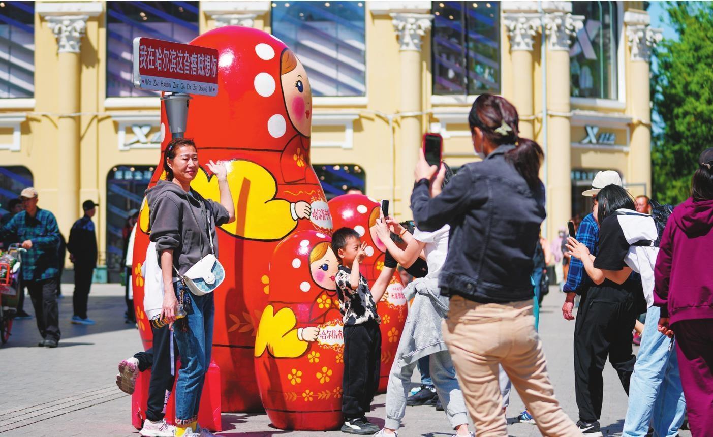 “五一”假期，游客在哈尔滨中央大街上留影。新华社记者 王建威 摄