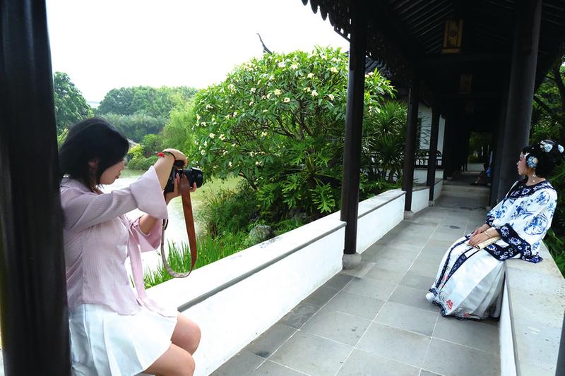     姜策兰（左）在南宁市花卉公园为小胡拍摄照片