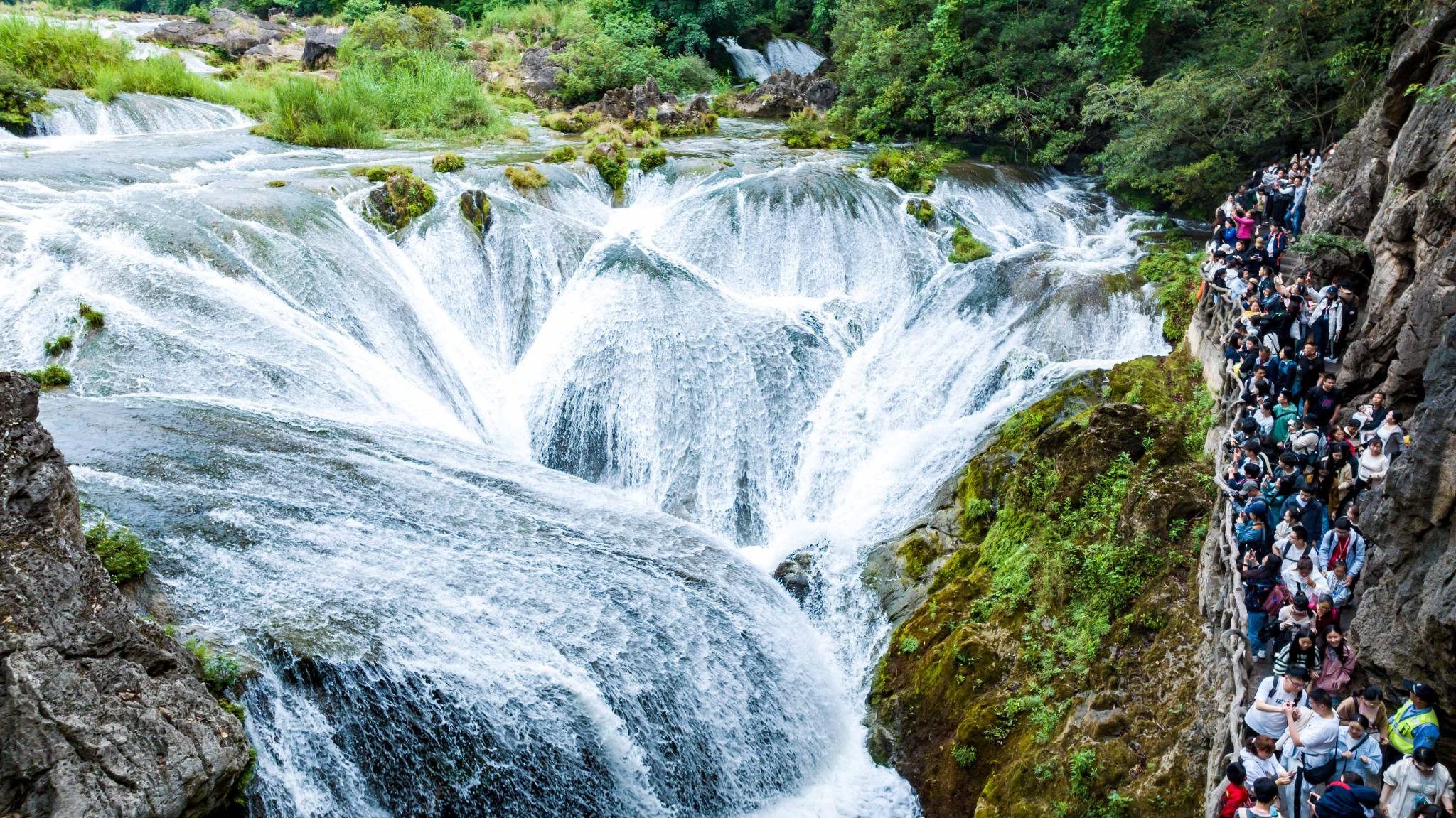 5月2日,游客在贵州省安顺市天星桥景区游览银链坠潭瀑布(无人机照片).
