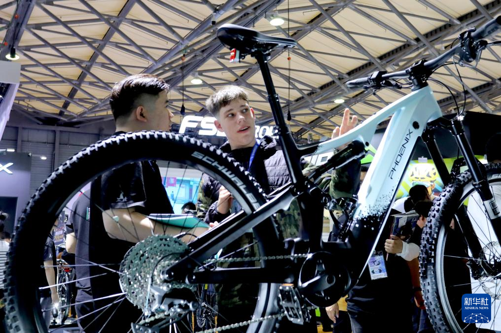 　　 5月5日，参观者在凤凰自行车展台上一辆电助力自行车旁交流讨论。