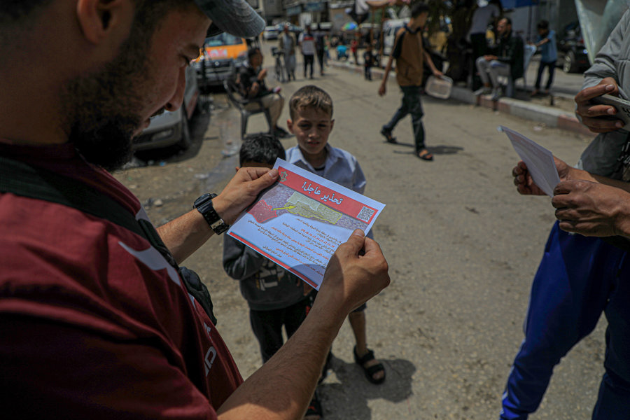 5月6日，在加沙地带南部城市拉法，人们查看以军发放的要求撤离的传单。 新华社 里泽克·阿卜杜勒贾瓦德 摄