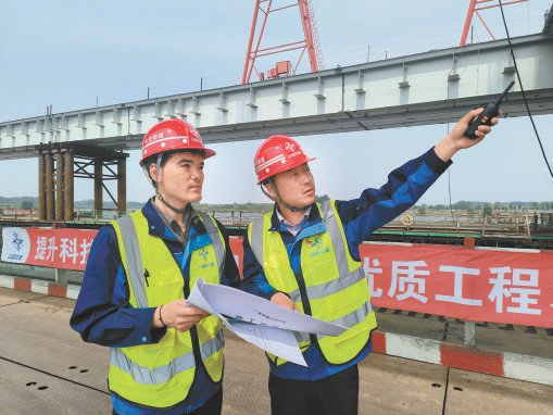 吴国梁（右）正和同事一起巡查施工现场。 中交路桥建设有限公司供图