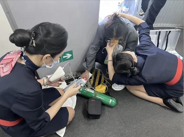 该旅客手扶廊桥桥壁,缓缓蹲下,手捂胸口,面容痛苦.