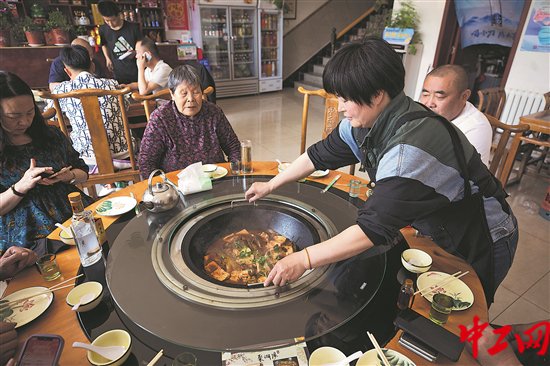 4月21日，河北省怀来县黑土洼村，一位经营农家乐的村民正在为顾客上菜。