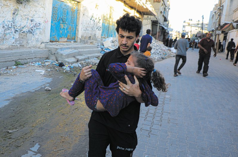 5月8日，在加沙地带南部城市拉法，一名男子转移一名受伤的儿童。 新华社发