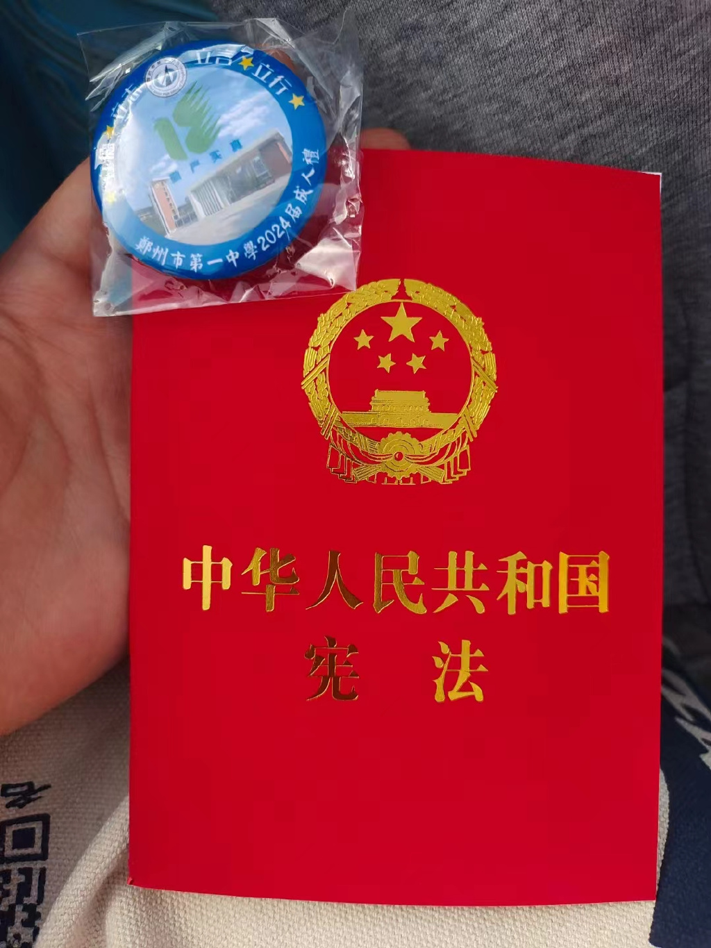 校长闫培新为学生代表赠送《中华人民共和国宪法》和成人纪念章,家长