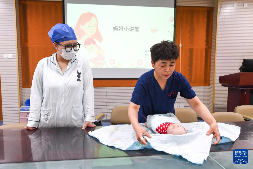 5月9日，新生儿科护士马凤丽（右）向新生儿母亲传授婴儿护理方法。新华社记者 张楠 摄