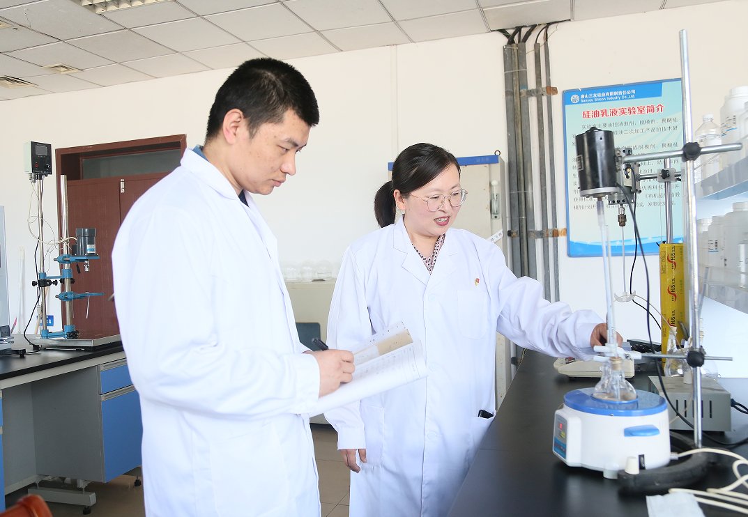 赵洁（右）与研发人员探讨嵌段硅油的制备技术