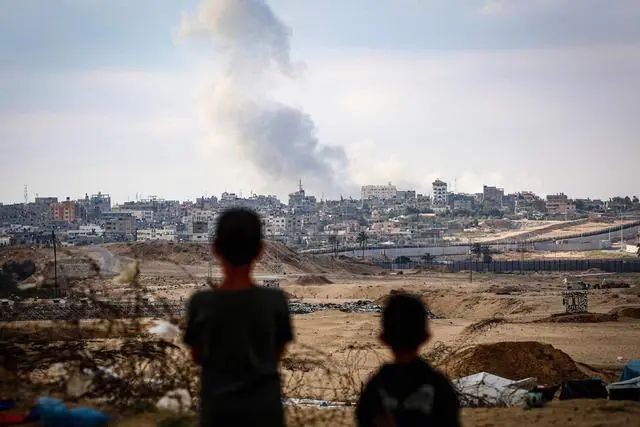 当地时间2024年5月13日，加沙地带拉法，巴以冲突持续，男孩们在以色列空袭中看着远处滚滚的浓烟。