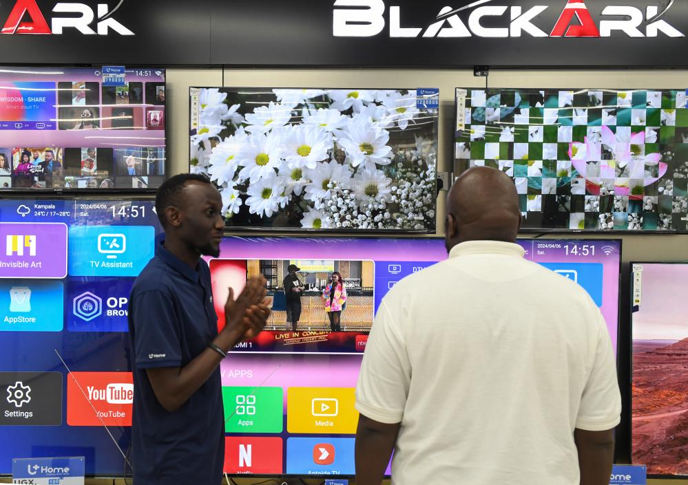 　　4月6日，在乌干达首都坎帕拉的UHome家电卖场，一名店员（左）为顾客介绍商品。新华社记者李亚辉摄