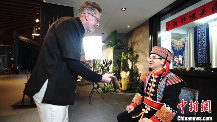 美国博主唐果果向恭城瑶族油茶习俗传承人周黎维(右)拜师学艺.