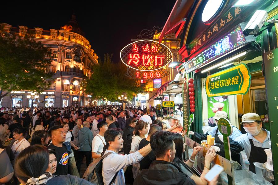 5月3日,游客在哈尔滨中央大街上的马迭尔冷饮厅购买冰棍