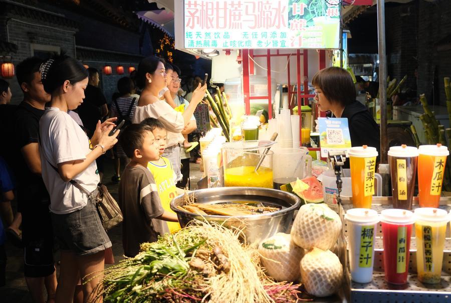 　　2023年10月，消费者在广西南宁市三街两巷等待购买食品。新华社记者 陆波岸 摄